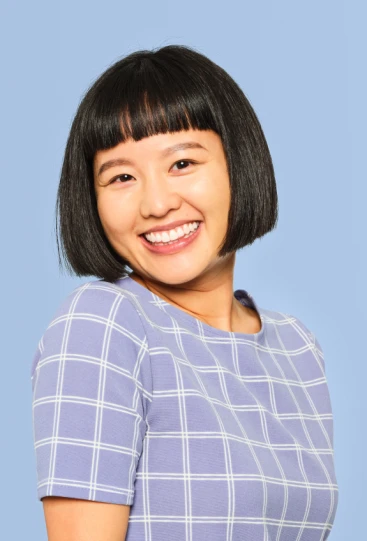 A woman with short black hair wearing a blue shirt, smiling and looking confidently at the camera.